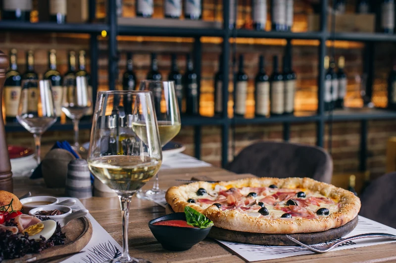 Pizza with prosciutto and olive with wine in restaurant